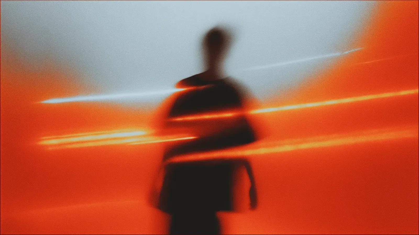 Blurred silhouette of a person walking through orange and red light